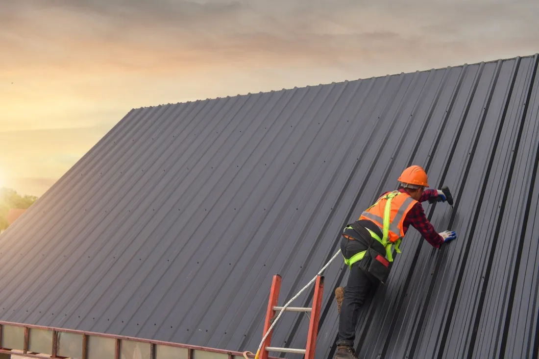 Dynasty roofing professional installing a new metal roof at sunset